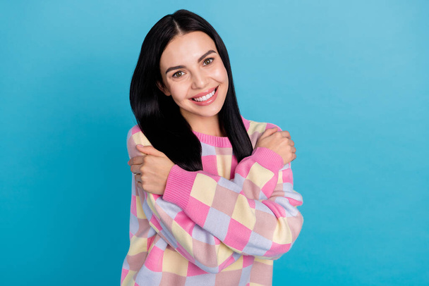 Photo of pretty sweet young woman wear pink sweater embracing herself isolated blue color background - Zdjęcie, obraz