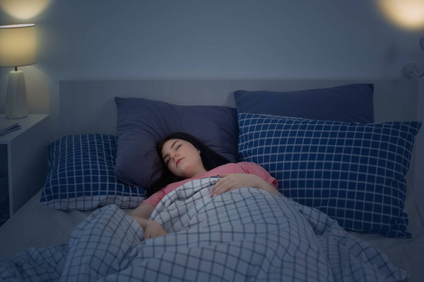 sleeping young brunette girl on bed in night - Photo, Image