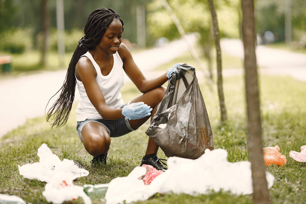 Teenage girl pick up trash at park - 写真・画像