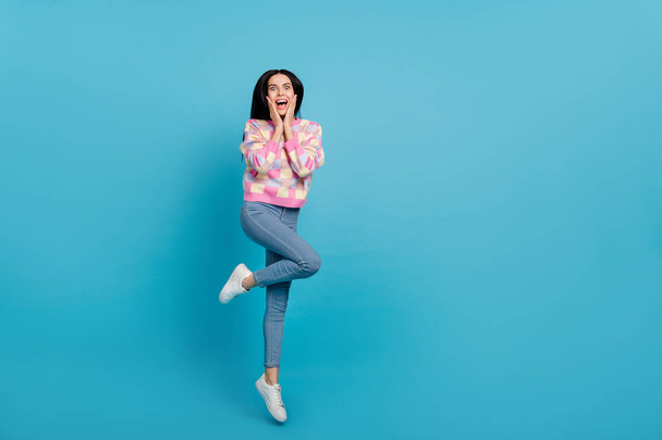 Photo of funny excited lady dressed print pullover arms cheeks jumping empty space isolated blue color background - Foto, Imagem