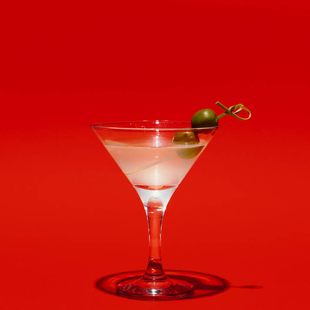 Martini glass with olives isolated on bright red neon background with shadow. Concept of taste, alcoholic drinks - Photo, Image
