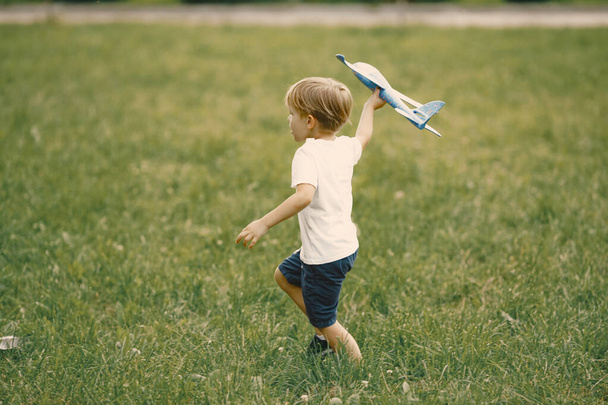 Little boy playing with airplane toy on a grass - Foto, imagen