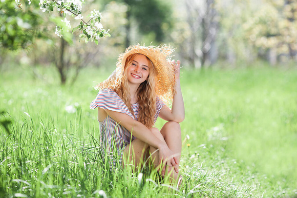 Aantrekkelijke jonge blonde vrouw buiten. Close-up portret van mooie dame zittend op het gras - Foto, afbeelding