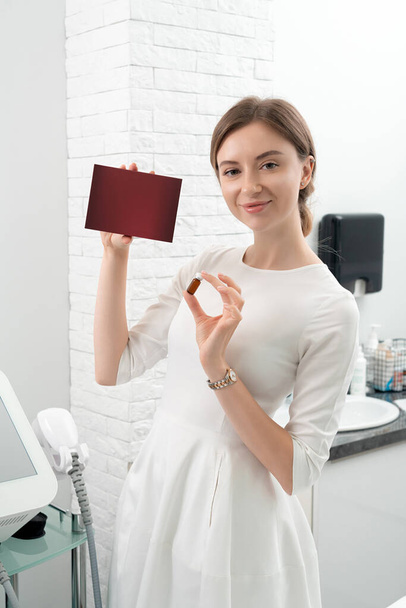 Cosmetologist dermatologist holds a package with drugs for facial rejuvenation. A female doctor in office shows treatment options. Mockup with copy space  - Photo, image