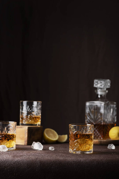 Bar concept: glasses of rum with ice and lemon on the brown background, selective focus image - Foto, afbeelding