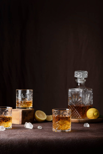 Bar concept: glasses of rum with ice and lemon on the brown background, selective focus image - Фото, изображение
