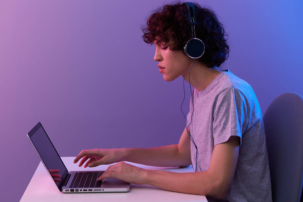 guy in headphones in front of laptop entertainment violet background - Foto, imagen