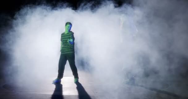 Dvě mladé tanečnice provádějící hip hop tanec ve zpomaleném filmu se světlem a kouřem pozadí - Záběry, video