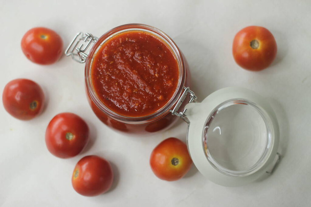 Kotitekoinen tomaattipastakastike tunnetaan myös nimellä punainen kastike lasipurkissa, jossa on kansi. Se valmistetaan leivontaan tomaatteja italialaisia yrttejä ja mausteita - Valokuva, kuva