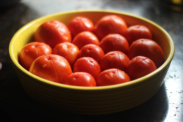 Gesplitste tomaten klaar om in de oven te houden voor het maken van rode saus pasta. Rode tomaten in gele plaat. - Foto, afbeelding