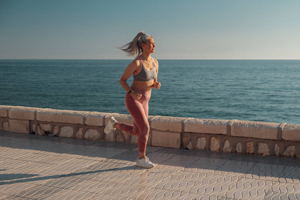 Sporty pretty lady jogging by the waterfront - Foto, Imagem