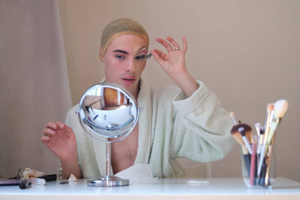 Drag queen person removing false eyelashes and wearing bathrobe. - Foto, afbeelding
