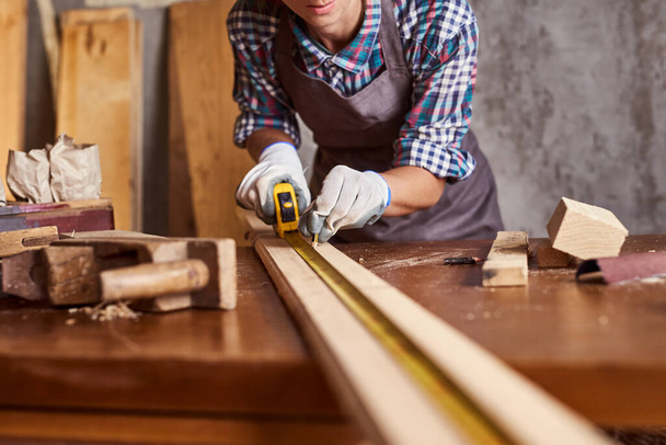 Female craftsmen use tape measure to assemble wooden pieces. Professional carpenter at work measuring wooden planks. - Foto, Imagem
