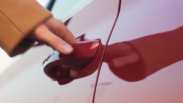 Nainen tuo kätensä punaisen auton ovenkahvaan ja avaa sen - Materiaali, video