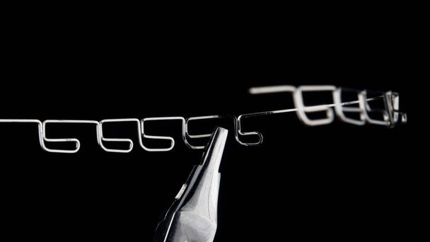 piękne makro zdjęcie wielopętlowego metalowego łuku ortodontycznego na czarnym tle - Zdjęcie, obraz