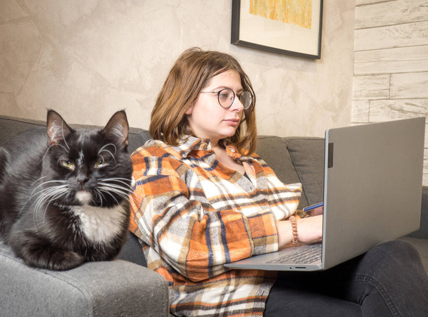 chica joven en gafas de trabajo en un ordenador portátil sentado en casa en la cama. - Foto, imagen