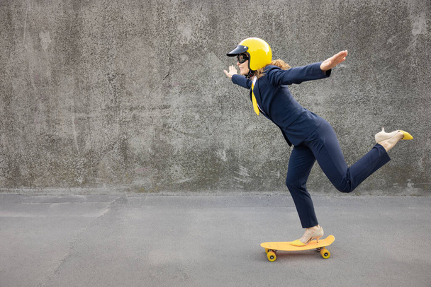 Happy businesswoman going to work. Funny young woman riding yellow skateboard outdoor. Back to work, start up and business idea concept - Foto, Imagem