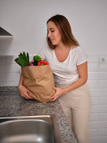 жінка залишає сумку на кухні після повернення з супермаркету
 - Фото, зображення