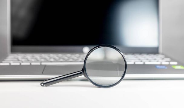 Laptop through magnifying lens. Internet search and SEO research concept - 写真・画像