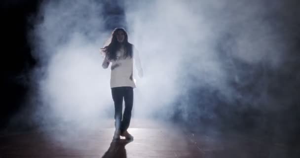 Giovane ballerina che esegue danza hip hop selvaggia con sfondo di luce e fumo - Filmati, video