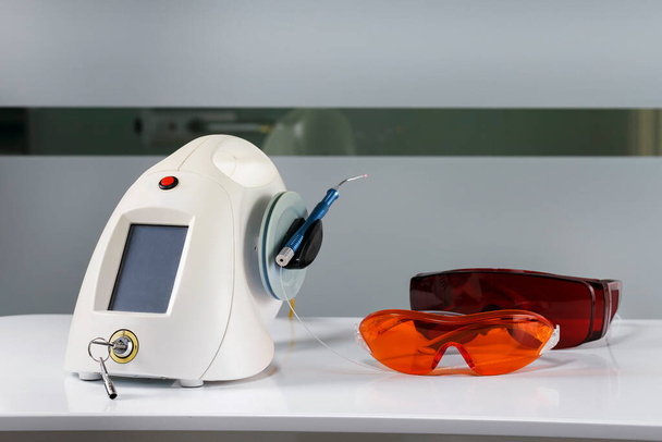 Dentallaser für die Operation auf einem Metalltisch und Schutzbrille für den Patienten - Foto, Bild