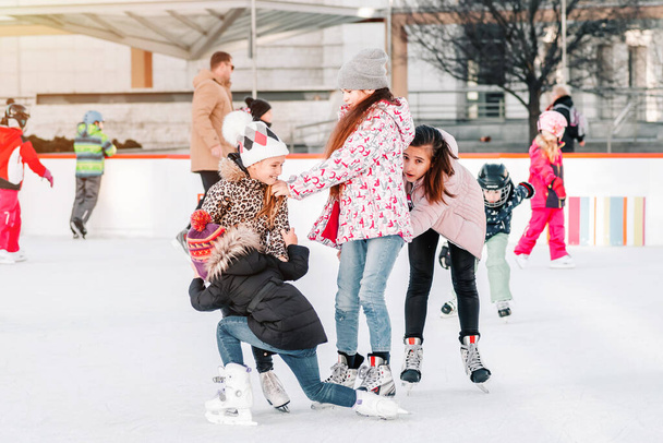 Puha, szelektív fókusz.Emberek, barátság, sport és szabadidő koncepció - boldog barátok a korcsolyapályán.Egy csapat tinédzser barátok korcsolyázás egy jégpályán. Vicces pillanat esett a jégpálya.  - Fotó, kép