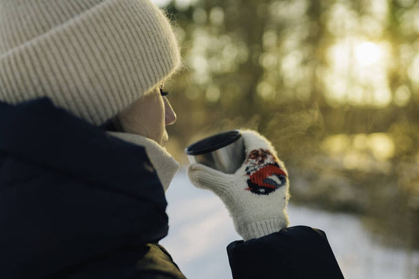 Woman drinking hot tea from mug in the winter forest, Winter holiday concept - Φωτογραφία, εικόνα