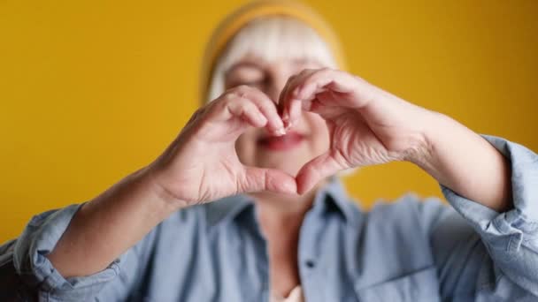 Hands making sign heart isolated over yellow color background. Love concept on Valentine day - Materiał filmowy, wideo