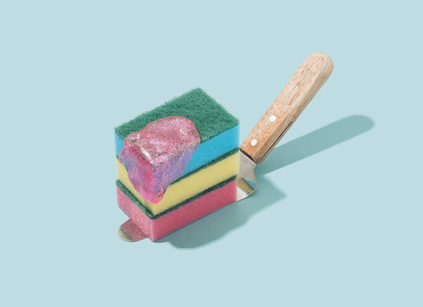 Cake spatula with colorful sponges and pink slime on a pastel blue background. Future past retro concept. - Фото, изображение