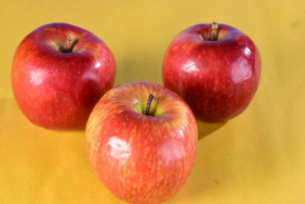 Sarı ve mavi arka planda izole edilmiş güzel kırmızı elmalar, sağlıklı doğal meyve - Fotoğraf, Görsel