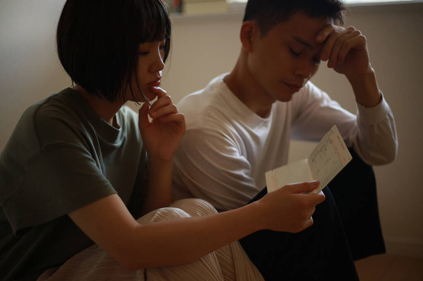 Una pareja preocupada mientras mira su libreta - Foto, Imagen