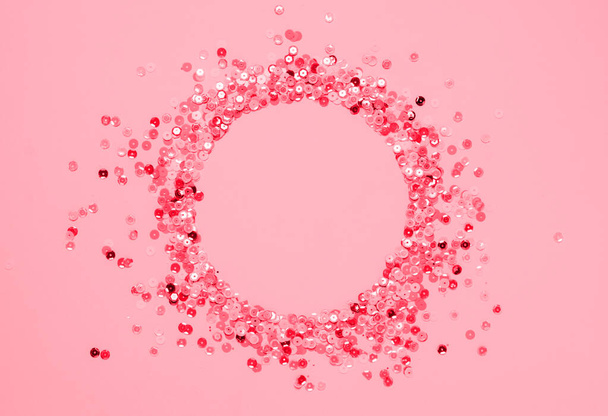 Sequins multicolored confetti lined in round frame pink background. Abstract festive composition place for text - Fotoğraf, Görsel