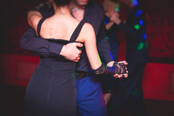 Couples dancing traditional latin argentinian dance milonga in the ballroom, tango salsa bachata kizomba lesson in the red and purple lights, dance festival - Foto, Imagem