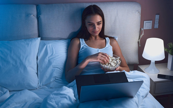 Woman with popcorn watching movie in bed - Zdjęcie, obraz