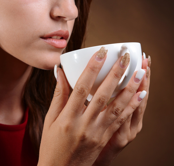 Beautiful young girl with cup of coffee on brown background - Foto, Imagen