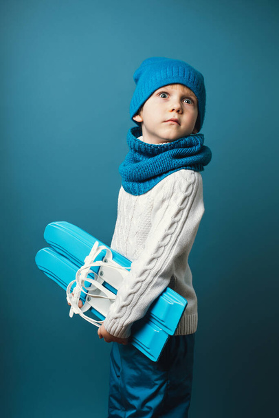 Verrast grappig kind met ski 's in handen. Concept van kinderrecreatie en sport, verticaal schot. - Foto, afbeelding