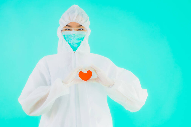 Portrait beautiful young asian doctor woman wear ppe or  personal protective equipment for protect from coronavirus or covid19 show heart on blue isolated background - Photo, Image