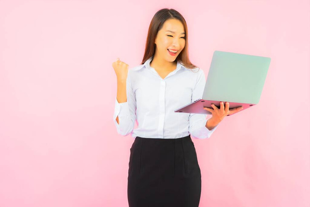 Retrato bela jovem mulher asiática com computador laptop na cor rosa fundo - Foto, Imagem
