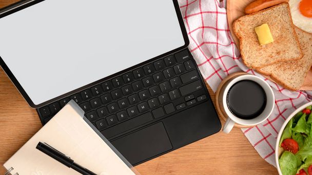 Top kilátás a modern munkaterület digitális táblagép, notebook, kávé csésze és reggeli készlet. - Fotó, kép