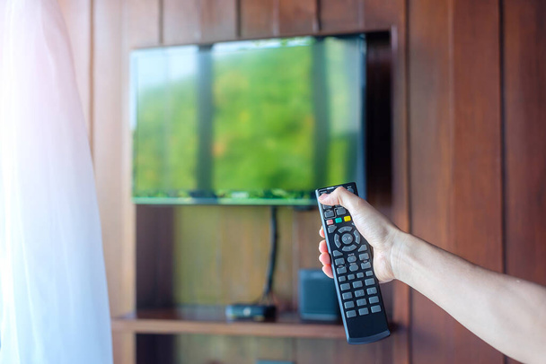 рука за допомогою пульта дистанційного керування для налаштування Smart TV всередині сучасної кімнати будинку або розкішного готелю
 - Фото, зображення