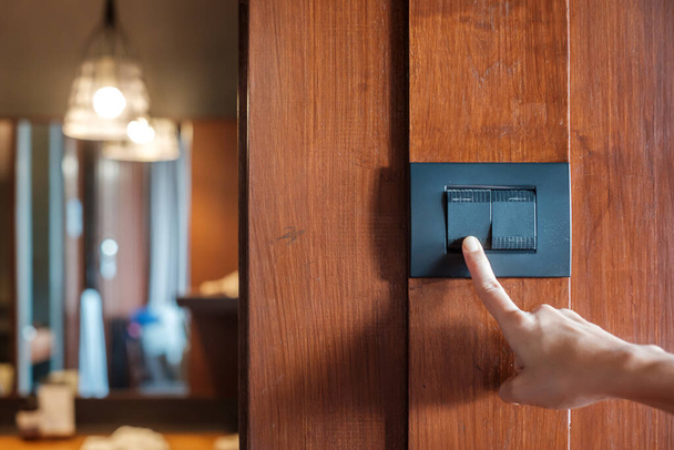 prst doma zapíná nebo vypíná vypínač světla na stěně. Energetické úspory, energie, elektrické a životní styl koncepce - Fotografie, Obrázek