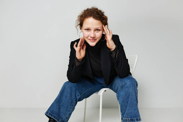 portrait of a young woman black jacket jeans posing light background unaltered - Foto, afbeelding
