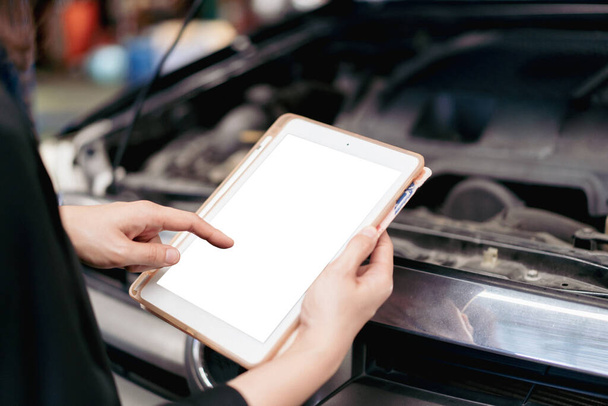 Asian young woman examining and using a digital tablet in vehicle repairing and diagnostic in garage. Woman trying to solve the car problem. - Foto, immagini