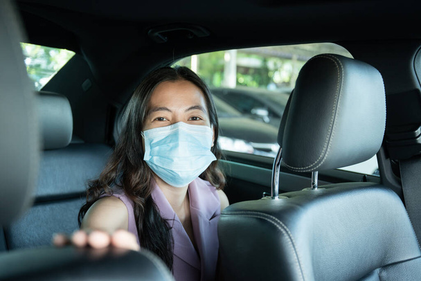 Belle femme d'affaires asiatique porter un masque protecteur d'hygiène prenant un siège arrière en taxi portrait, heureuse femme asiatique passager avec masque facial voyageant en taxi lors de la pandémie COVID-19. - Photo, image