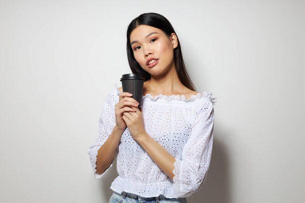 Charming young Asian woman a black glass in the hands of a drink like a smile isolated background unaltered - Fotografie, Obrázek