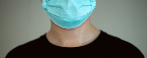 Unrecognizable Asian young man in black shirt wearing a protective face mask looking at camera close up. Wearing a face mask during the COVID-19 or coronavirus 2019 pandemic. - Foto, imagen