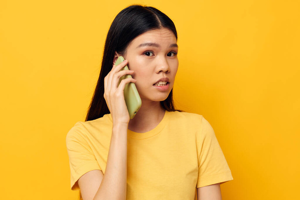 woman with Asian appearance phone communication fun use yellow background unaltered - Foto, Bild