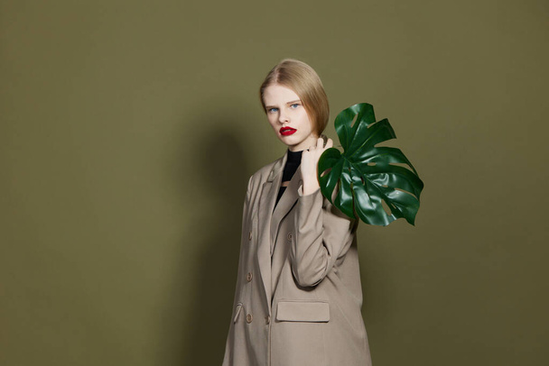 fashionable woman green palm leaf coat bright makeup studio model unaltered - Foto, Bild
