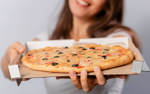Mise au point sélective, gros plan d'une pizza coupée en morceaux dans une boîte à mains féminines isolée sur un fond blanc. - Photo, image