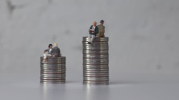 Miniatűr férfiak és miniatűr nők különböző magasságú érméken ülnek. A nemek közötti bérszakadék fogalma. - Felvétel, videó